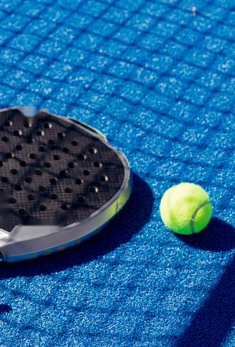 Padel racket and ball on a blue court